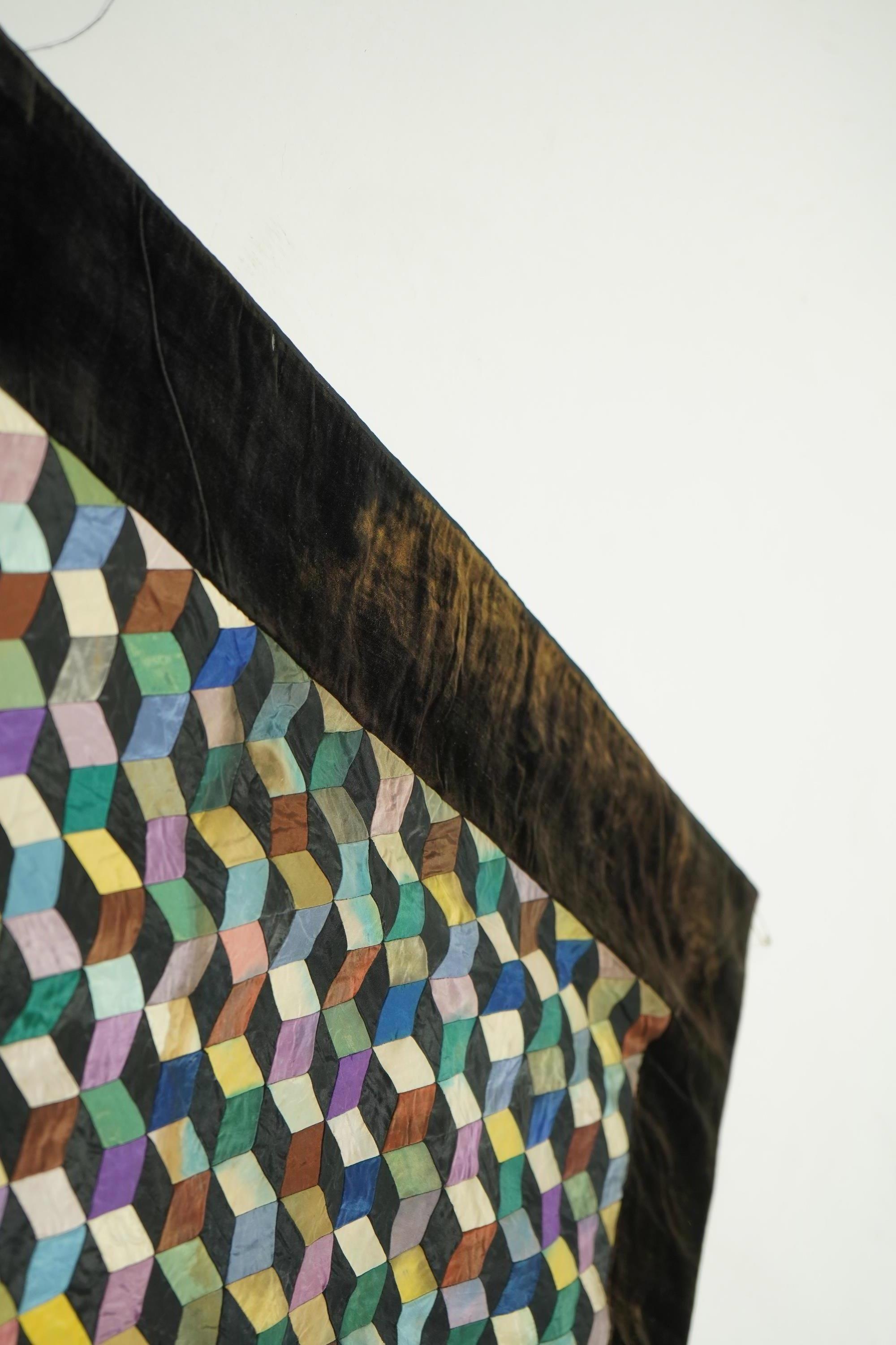 An English 19th century silk ‘Tumbling Blocks’, hand sewn, patchwork quilt, with central star motif and wide velvet border. Worked with multi coloured silks backed with black and blue silk., 170cm x 152cm. Condition - th